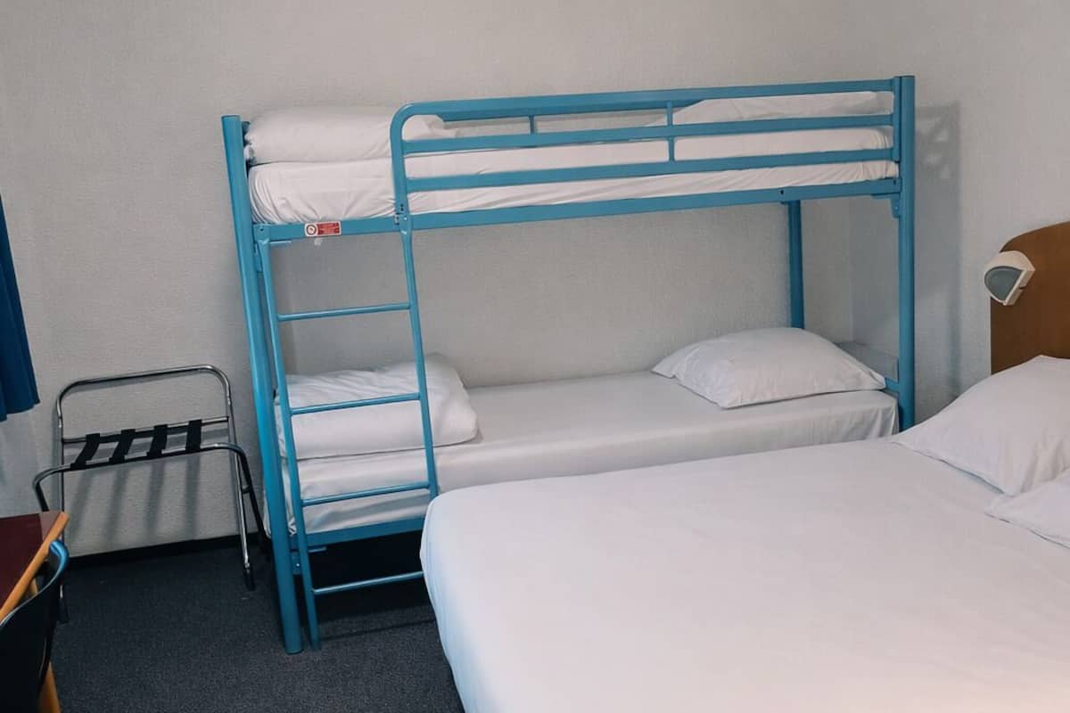 A room with bunk beds, a desk, and a chair.