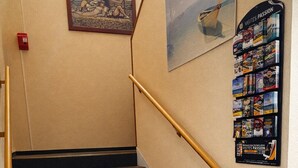 A staircase with a handrail, a framed picture on the wall, and a travel book rack. - Quick Palace St Brieuc Tregueux (Tregueux)