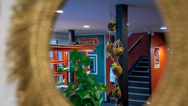 Udsigt gennem et rundt vindue af en trappe, der fører til en platform med et skilt, der står "Chambres 10 à 130".