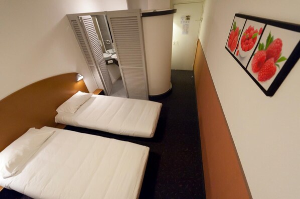 A hotel room with a bed, a small bathroom, and a wall-mounted picture of strawberries.