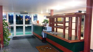 A reception area with a glass door labeled "POUSSEZ," a small counter with a plant, and a display case with magazines. - Quick Palace Vannes (Vannes)