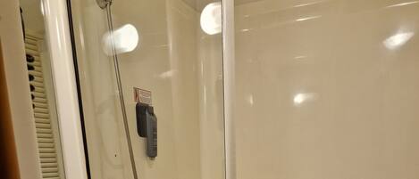 A bathroom with a sink, mirror, and shower.