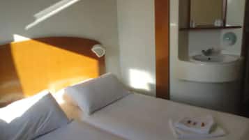 A hotel room with a bed, a nightstand, a mirror, and a sink.