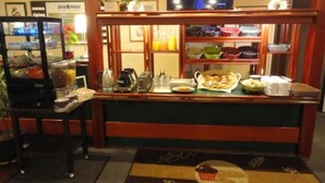 A hotel reception area with a coffee station, a television displaying a scenic view, and a sign reading "Quick Palace". - Quick Palace Epinal (Epinal)