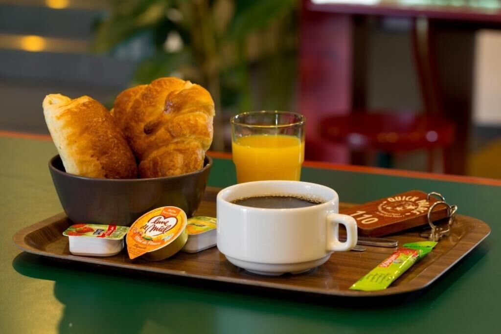 A breakfast tray with croissants, orange juice, coffee, and condiments.