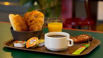 A breakfast tray with croissants, orange juice, coffee, and condiments.