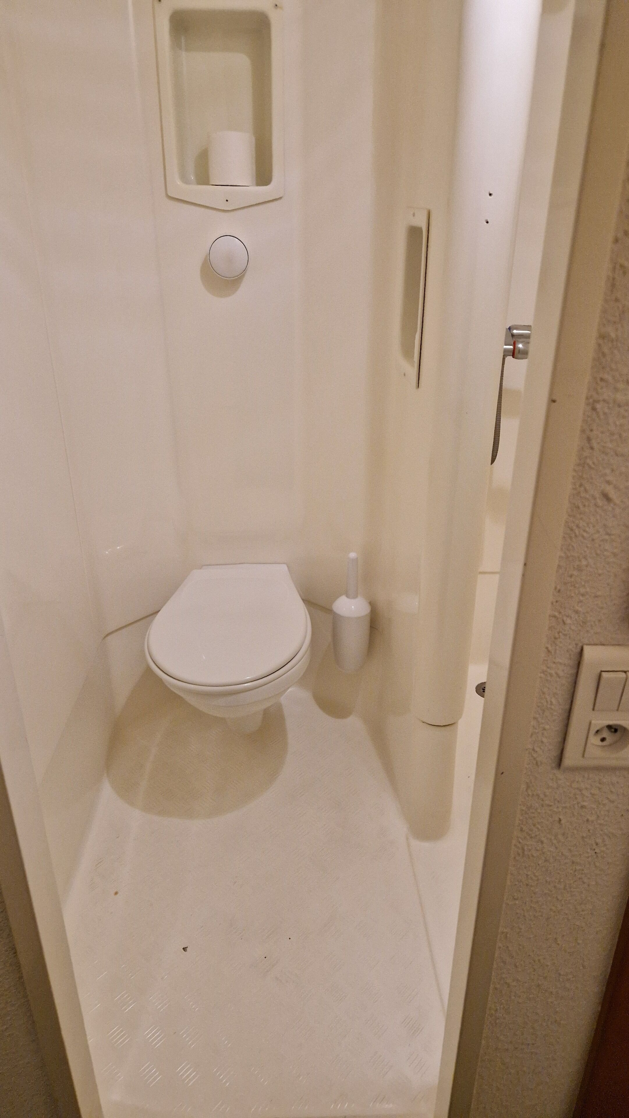 A small, enclosed bathroom with a toilet and a toilet paper holder.
