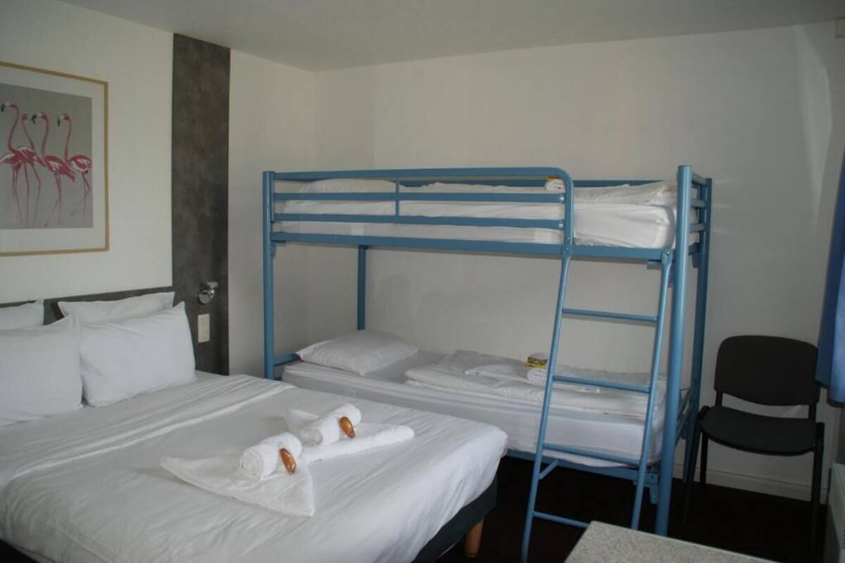 A hotel room with a bunk bed, a single bed, and a chair.