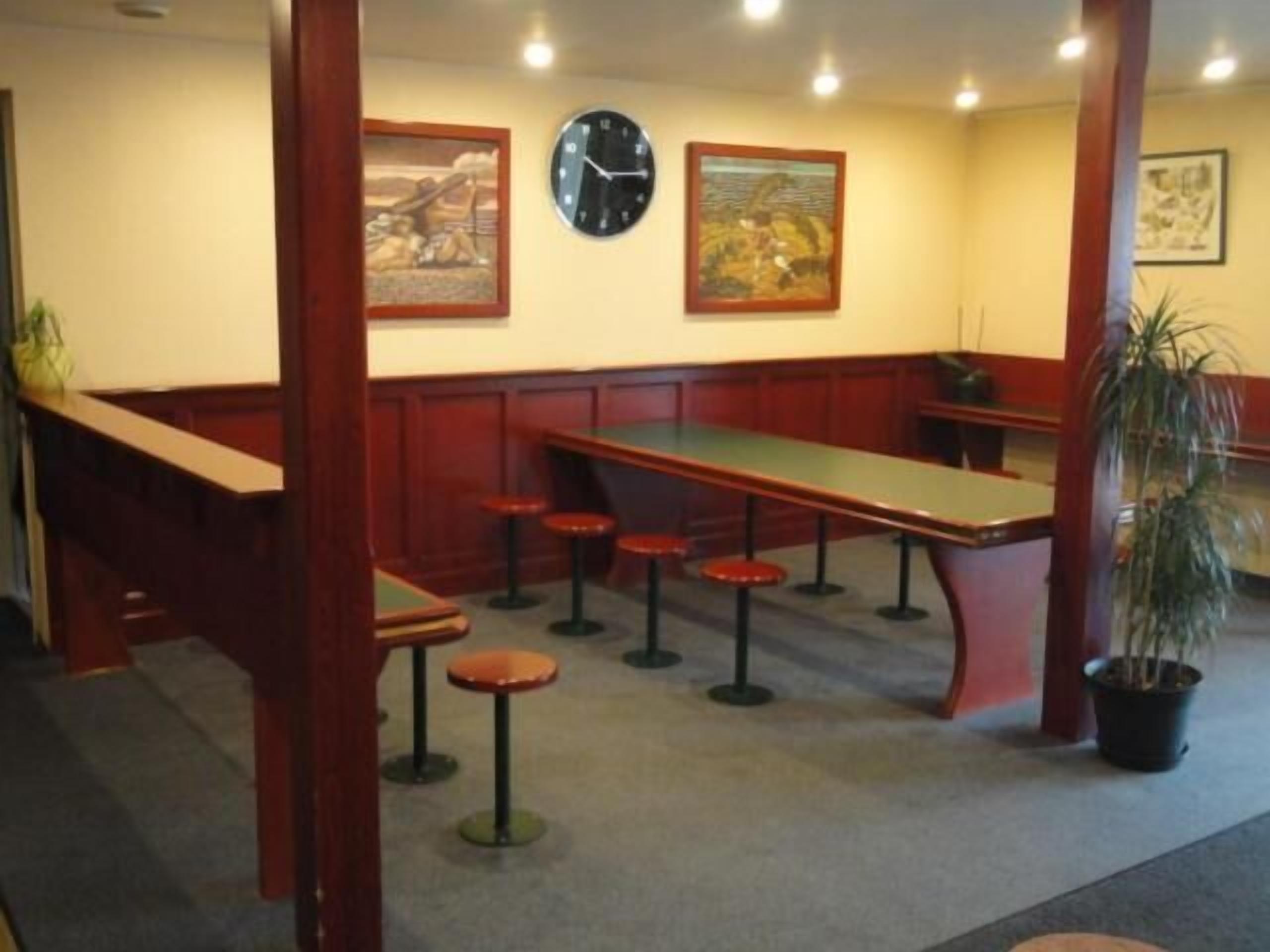 Un restaurant avec un long comptoir, des tabourets et deux horloges au mur.