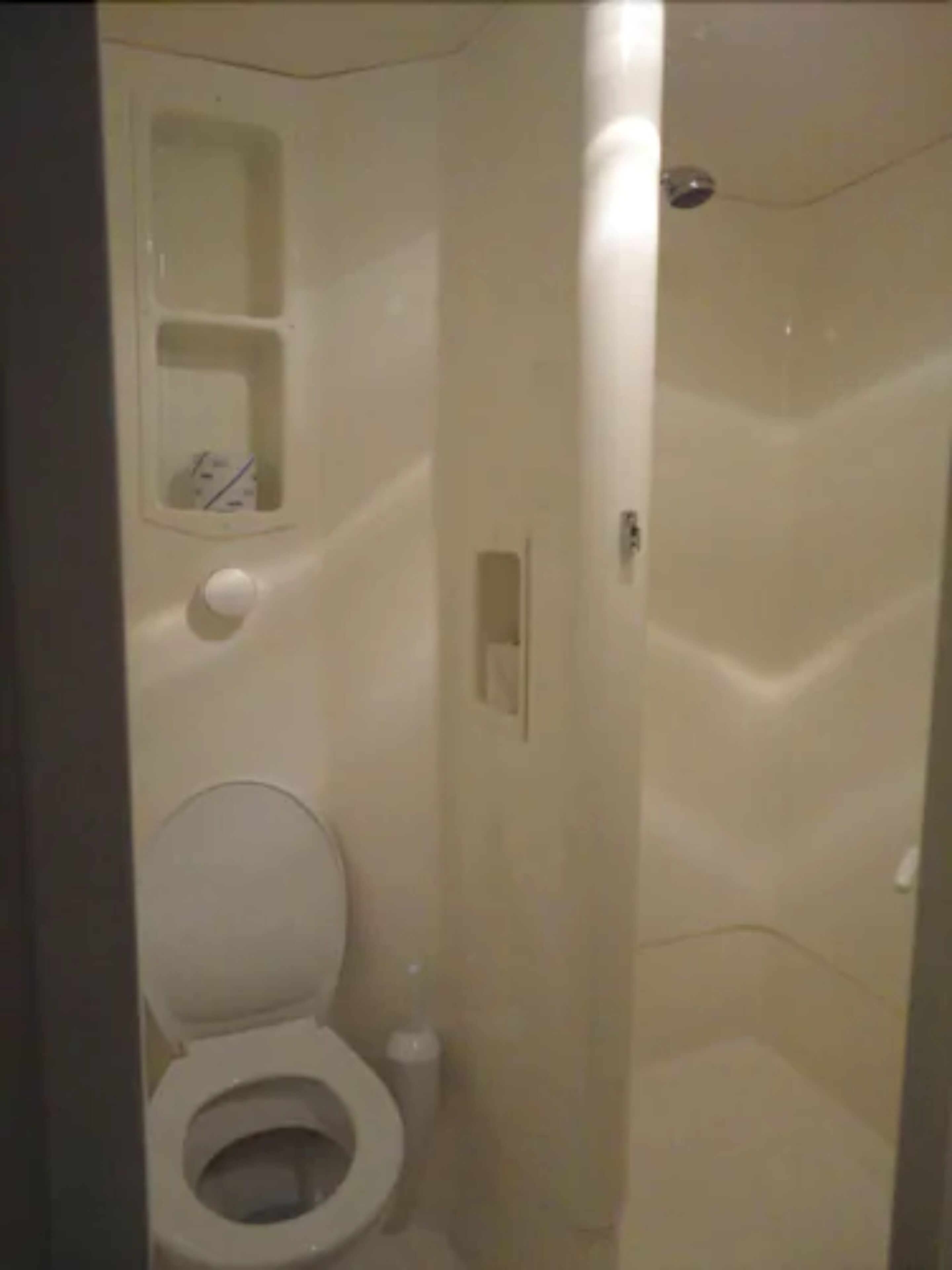 Un baño pequeño y cerrado con inodoro, lavamanos y cabina de ducha.