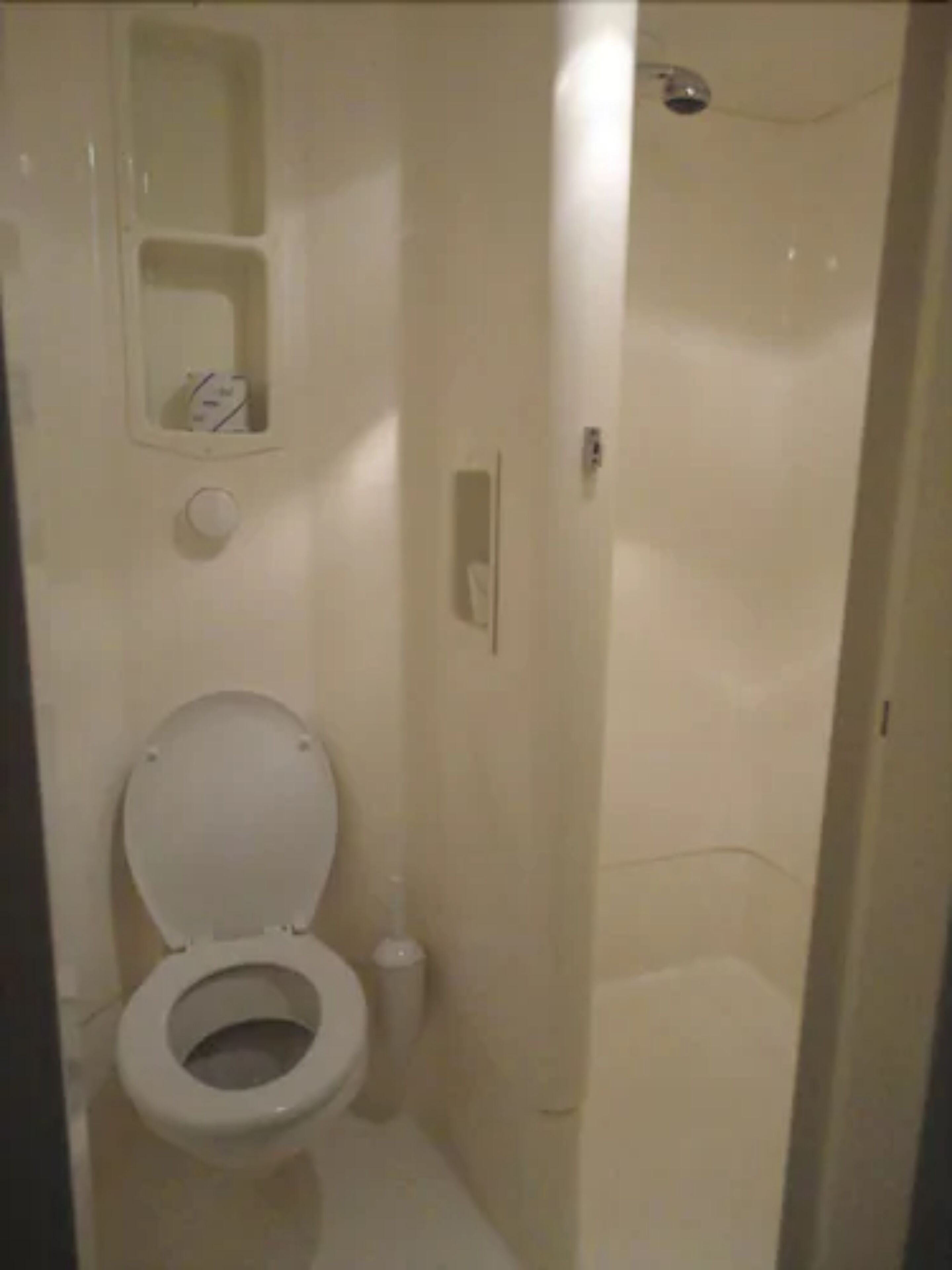 Ein kleines, kompaktes Badezimmer mit Toilette, Waschbecken und Duschkabine.