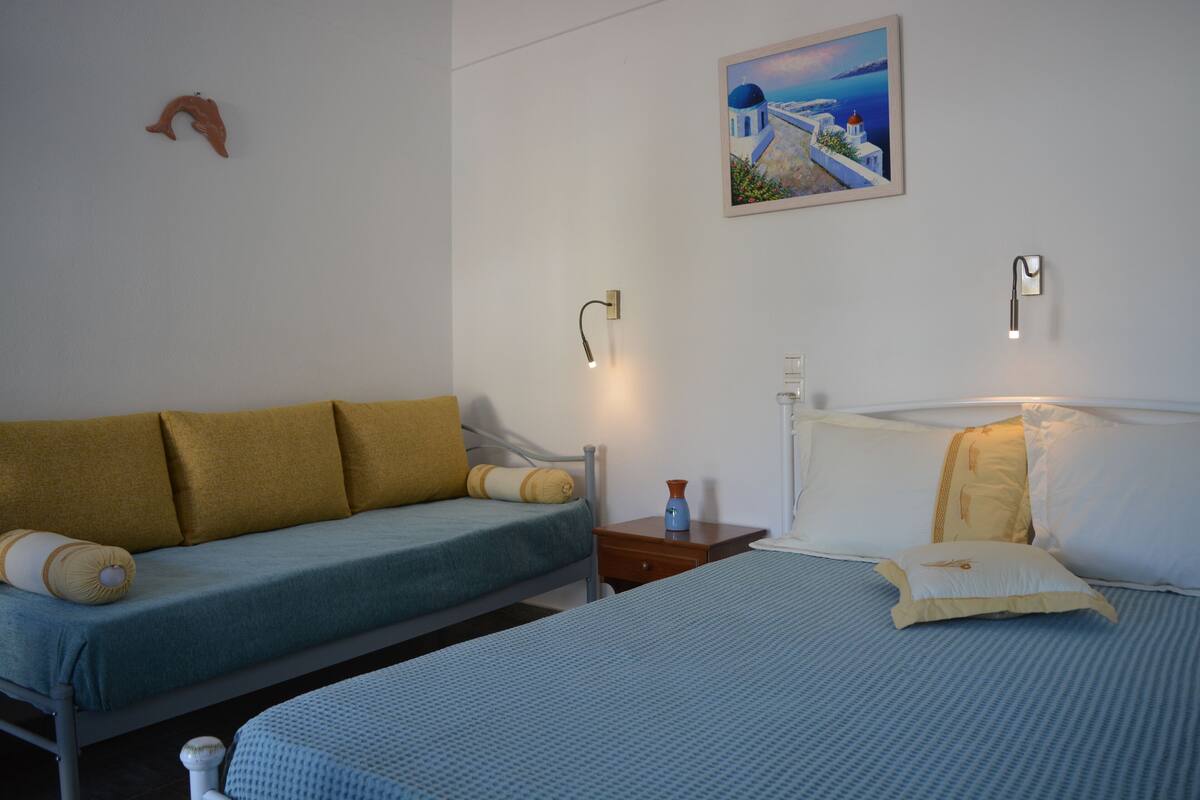 A bedroom with a bed, a sofa, and a nightstand.
