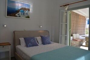 A bedroom with a bed, a nightstand, a painting, and a view of the outside.