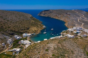 An aerial view of a coastal village with buildings, a narrow waterway, and boats.