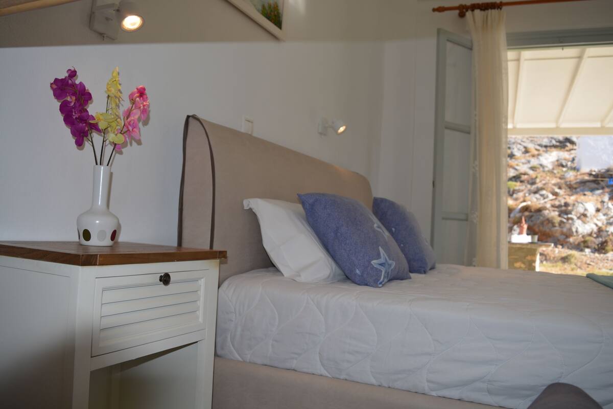 A bedroom with a bed, a nightstand, and a vase with flowers.