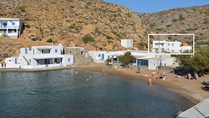 Ein Küstendorf mit weißen Häusern, einem Strand und felsigen Hügeln.