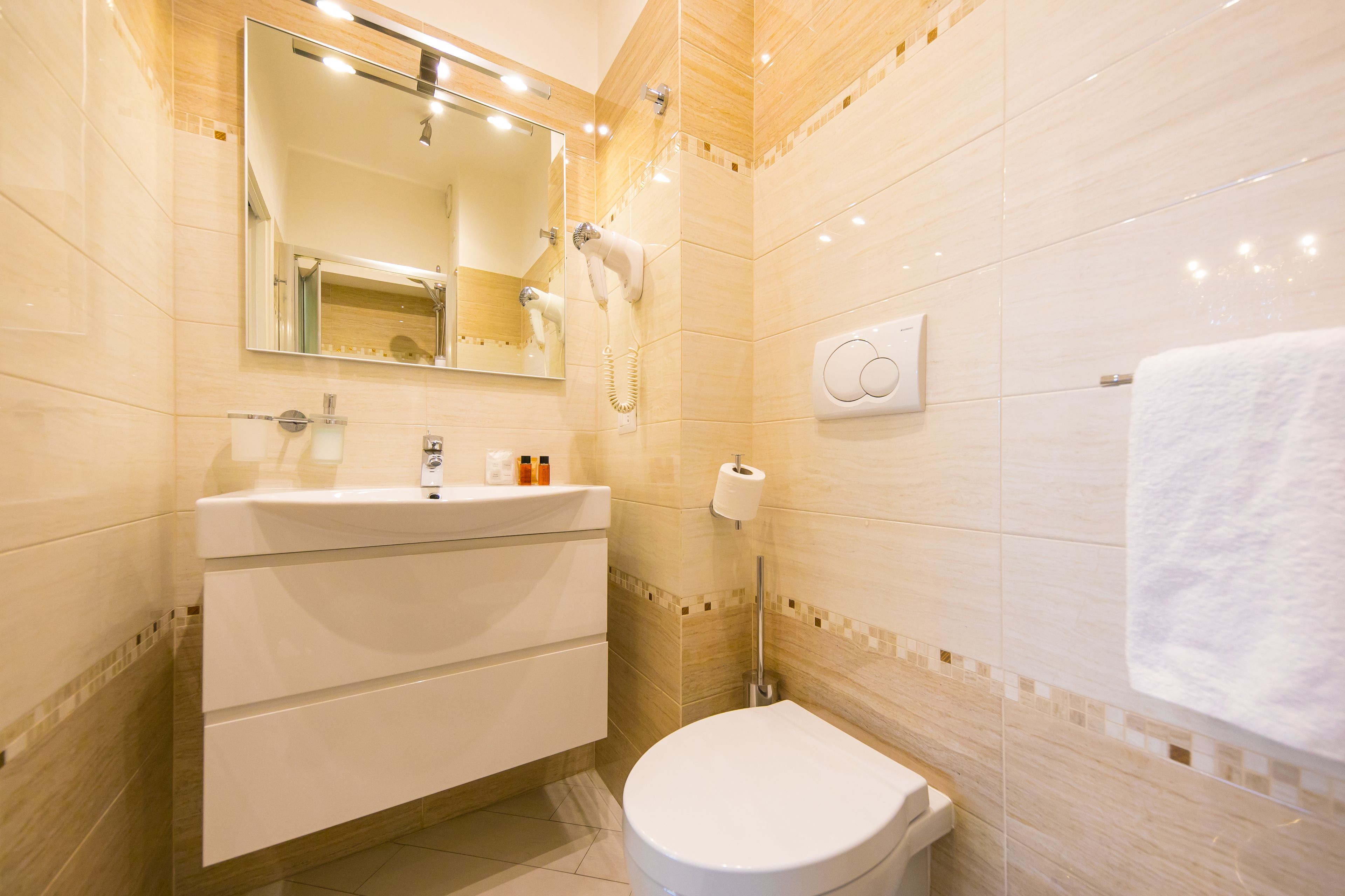 Un baño moderno con un lavamanos, espejo y retrete blancos.
