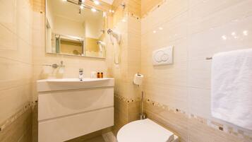 Un baño moderno con un lavamanos, espejo y retrete blancos.