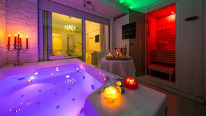 Un cuarto de spa con una bañera grande, velas y un banco de madera.