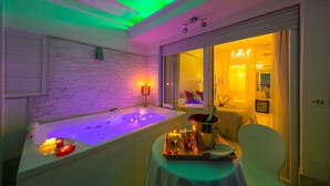 Un cuarto de spa con una bañera, velas y una bandeja con una botella y copas.