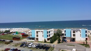 Un hôtel situé sur la côte, avec une fa çade bleue, un parking et une vue sur la mer.