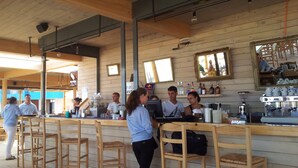 Un café aux murs en bois, avec des tabourets de bar, une machine à café et un comptoir où le personnel sert les clients.