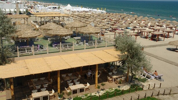 Un restaurant situé en bord de mer, avec une terrasse, des parasols et une vue sur l’océan.