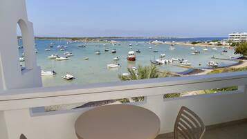 Un balcon avec une table et des chaises donnant sur une marina où sont amarrés de nombreux bateaux.