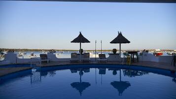 Una piscina al aire libre de temporada, sombrillas