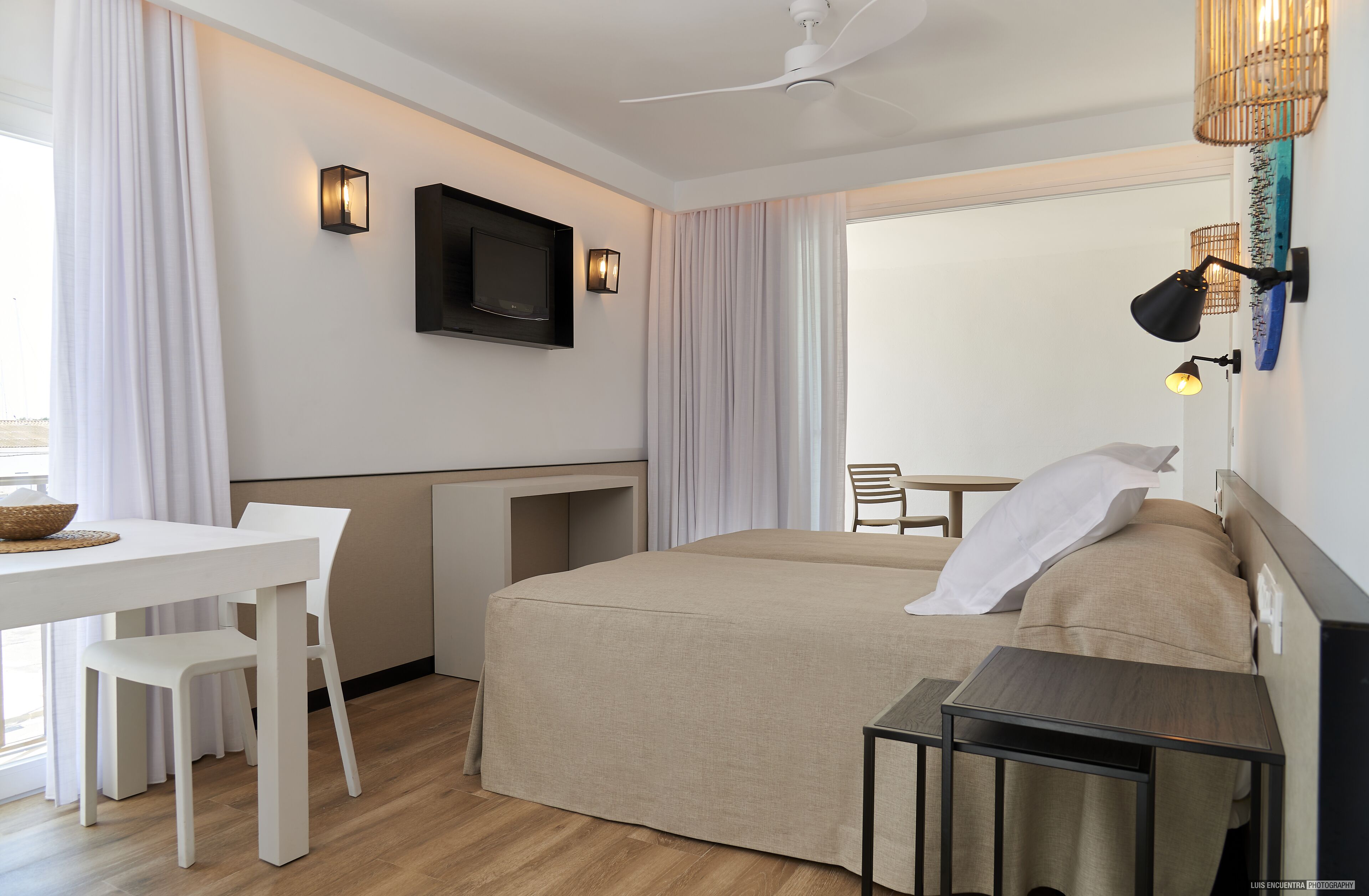 Une chambre d’hôtel équipée d’un lit, d’un bureau, d’une chaise, d’une télévision et d’une fenêtre avec des rideaux.