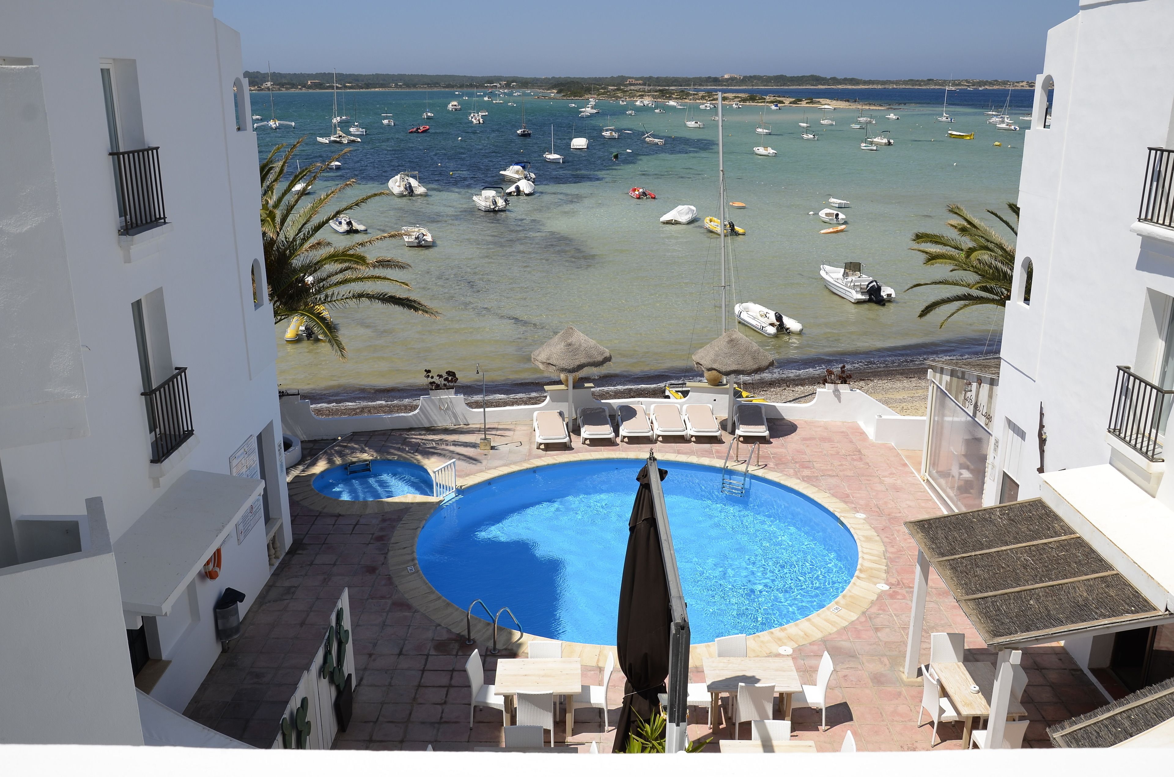 A pool area with lounge chairs and umbrellas, overlooking a marina with boats.