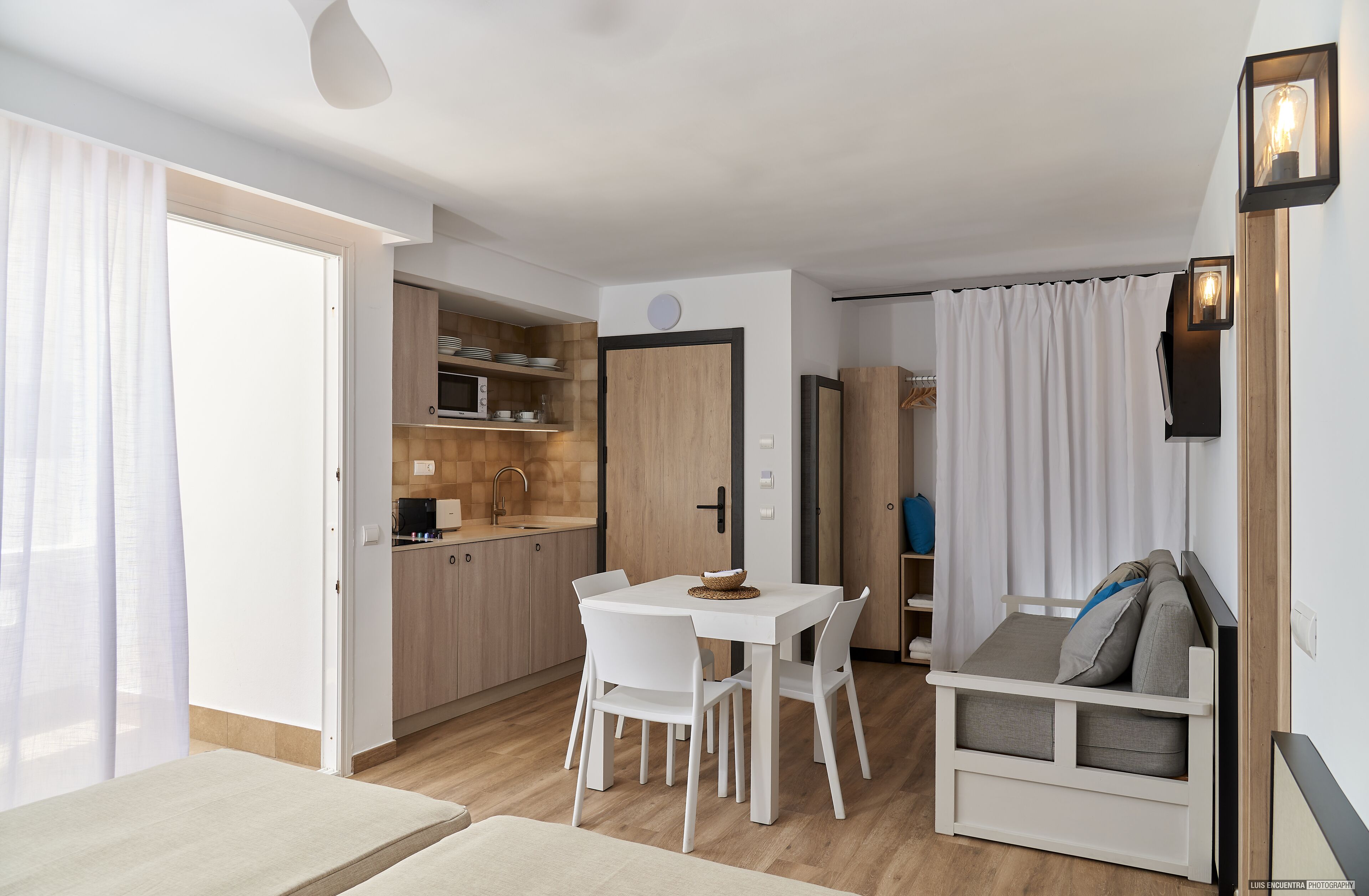 A compact living space with a kitchenette, dining area, and a sofa bed.