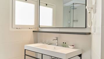 Un baño moderno con un lavabo blanco, un espejo, un perchero para toallas y una ducha.