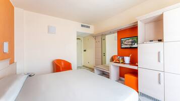 Ein Hotelzimmer mit Bett, Schreibtisch, Stuhl und Kleiderschrank.