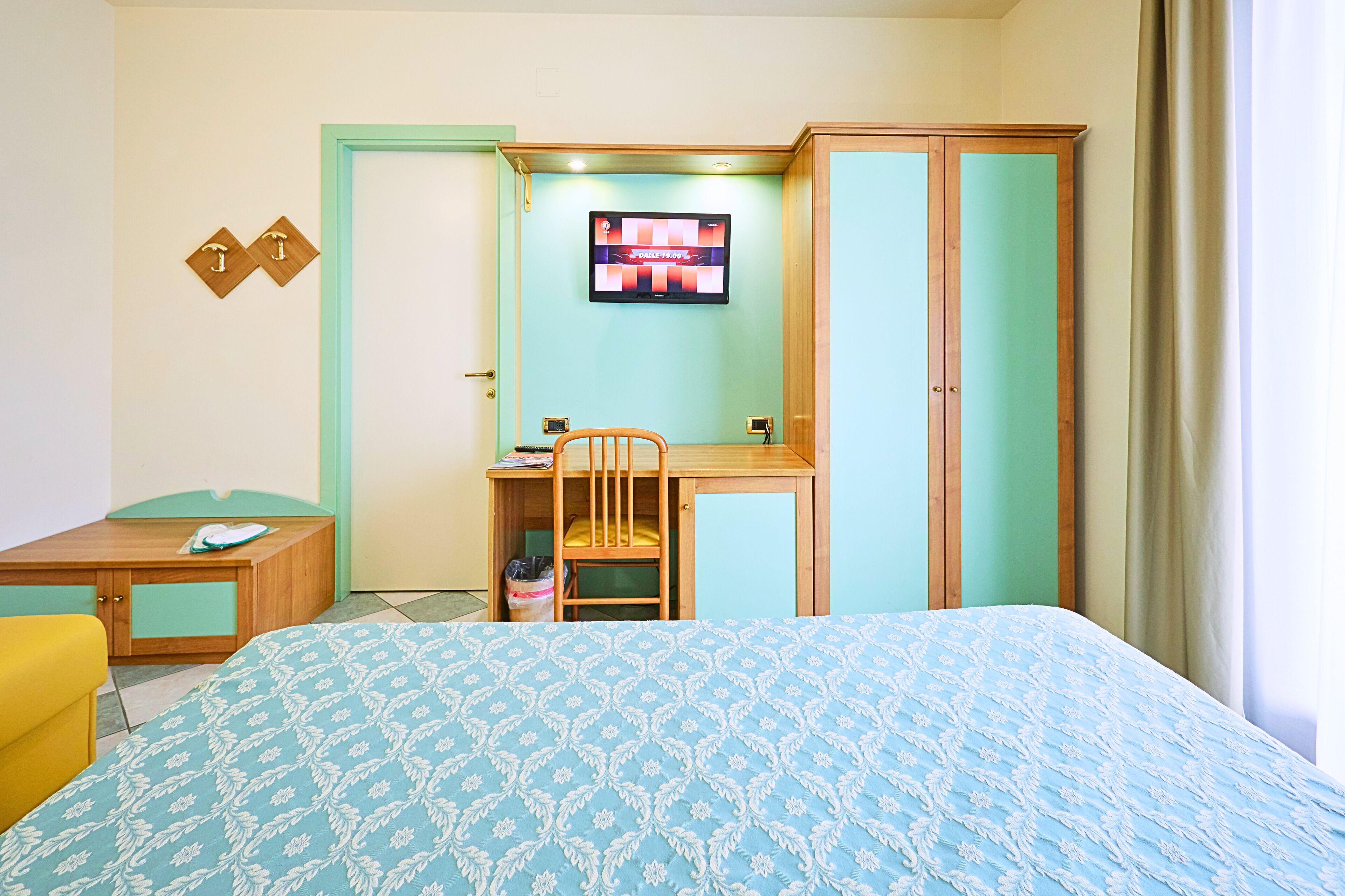 A room with a bed, a desk, a chair, and a television.