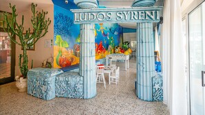 A children's play area with a mural, seating, and a sign reading "LUDOS SYRENI". - Hotel Villa Elena (Tortoreto)