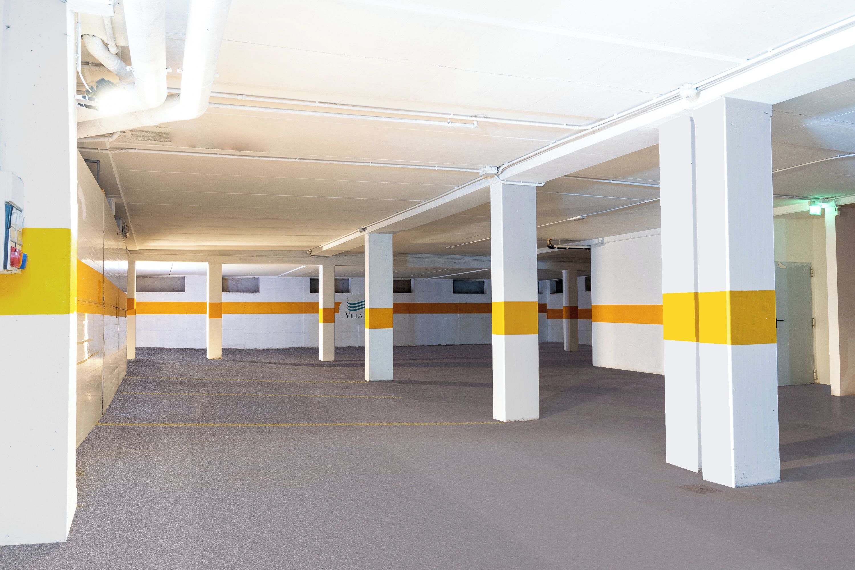 Un parking aux piliers blancs et aux bandes jaunes, doté d’un design épuré et moderne.