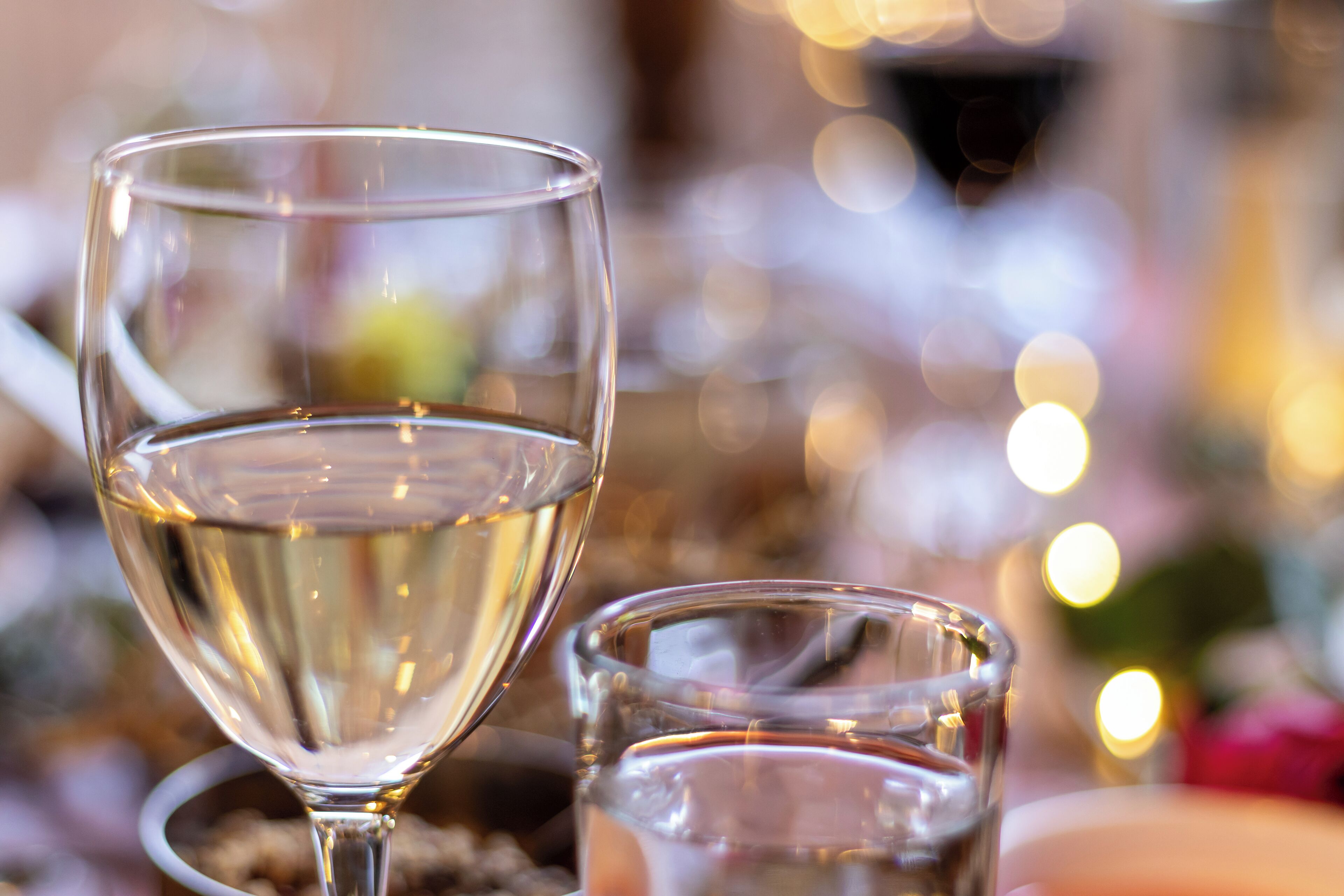 Un primer plano de dos copas de vino blanco sobre una mesa.