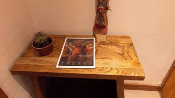 Una pequeña mesa de madera con un libro, una cactus en maceta y una figura decorativa.