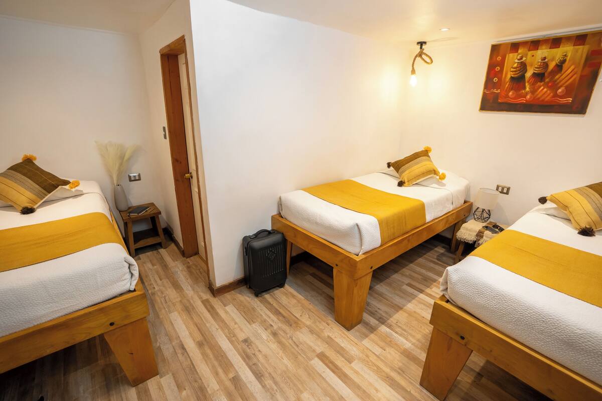 Hotellihuone, jossa on kaksi erillistä sänkyä, puiset päätyosat ja pieni yöpöytä, jossa on lamppu.