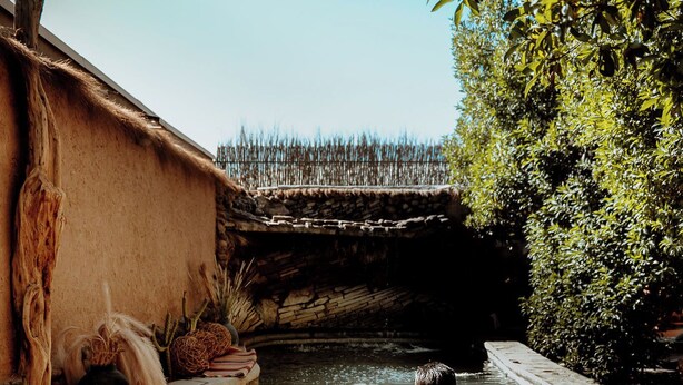 A stone pool with a man and a woman sitting at the edge. - Don Raúl (San Pedro de Atacama)