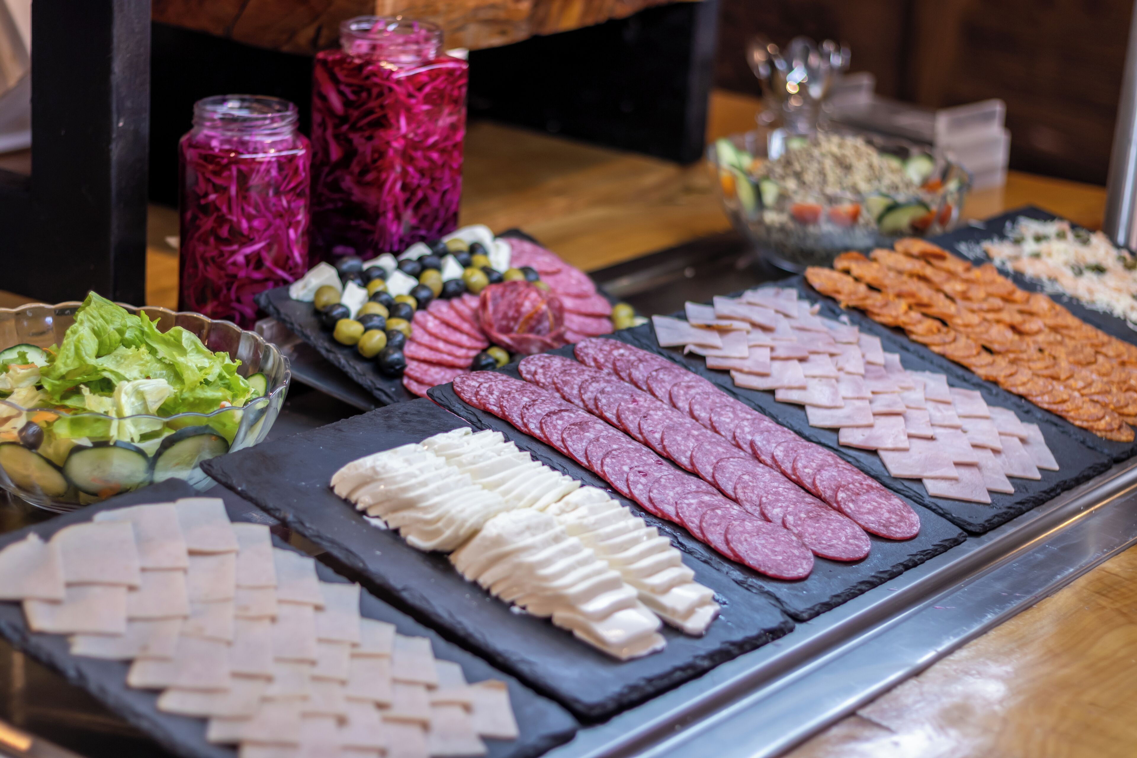 Un bufé con diferentes opciones de comida, como carnes, quesos y ensaladas.