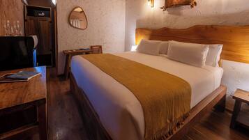 A cozy room with a large bed, wooden headboard, and a small table with a book.