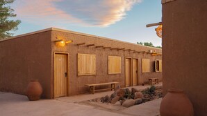 A rustic building with wooden doors and windows, a bench, and two large vases. - Don Raúl (San Pedro de Atacama)