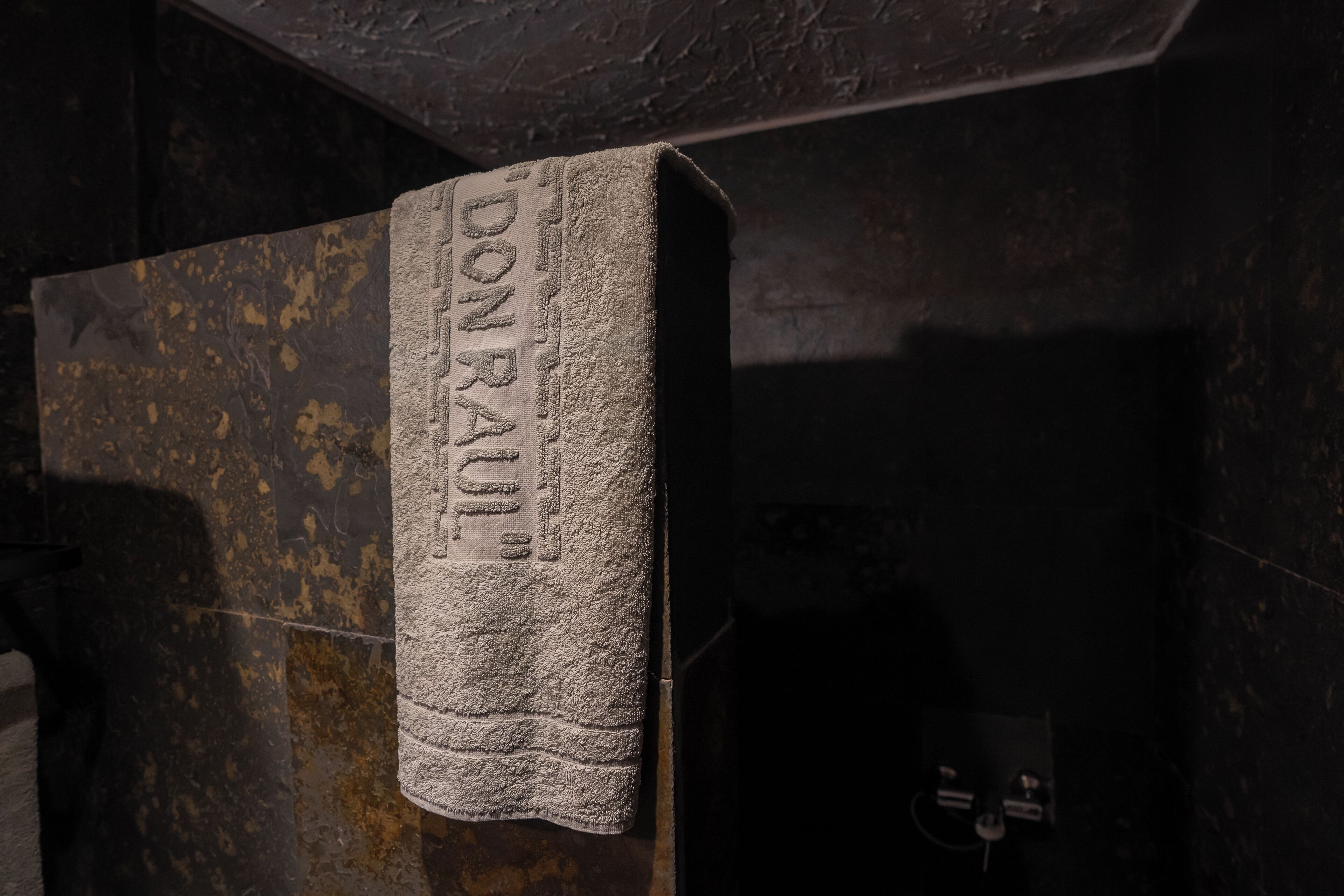 A towel hanging on a textured wall with the inscription "DON'T RAKE".