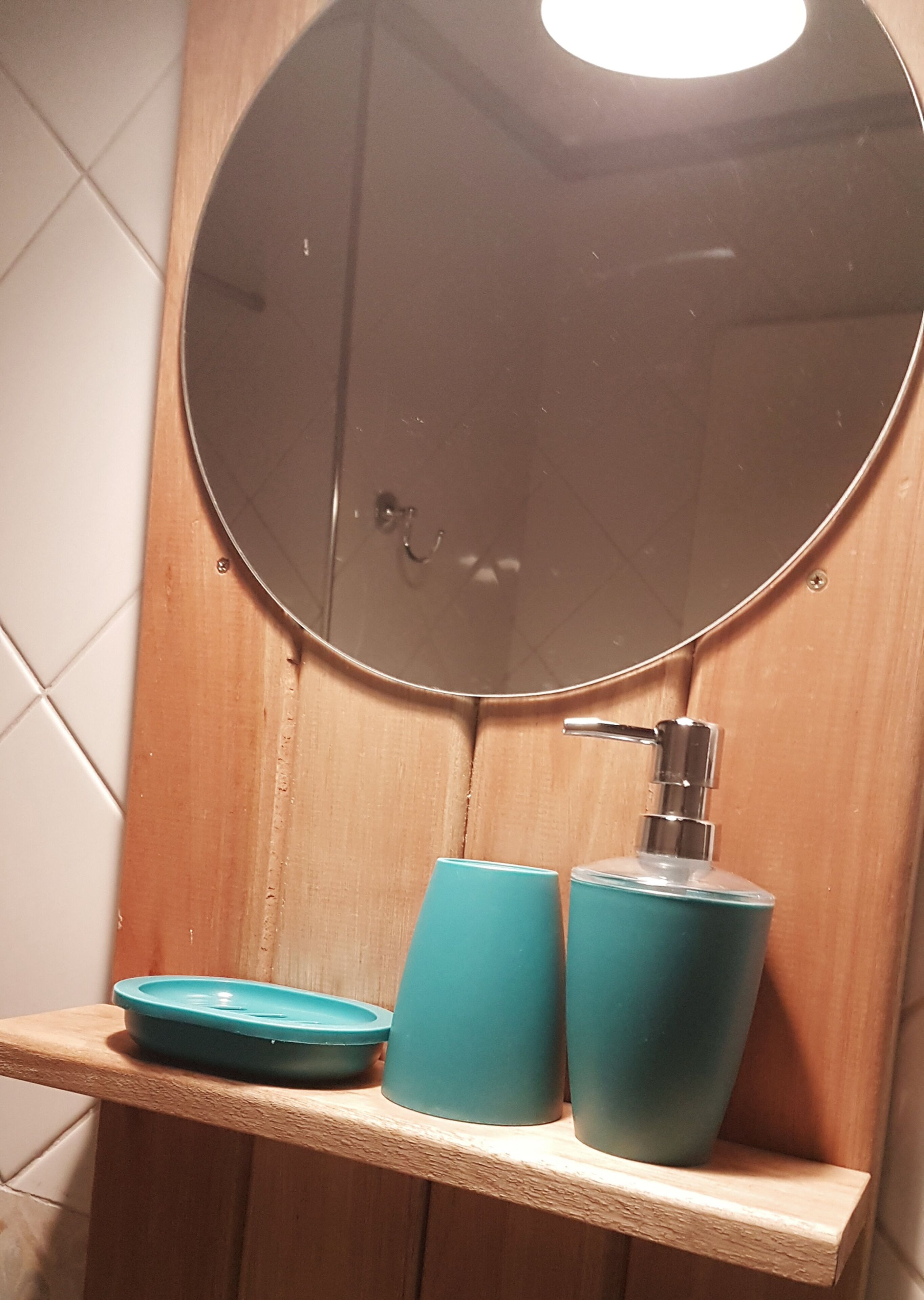 Kylpyhuone, jossa on puinen allaskaappi, pyöreä peili ja hana, jossa on allas.