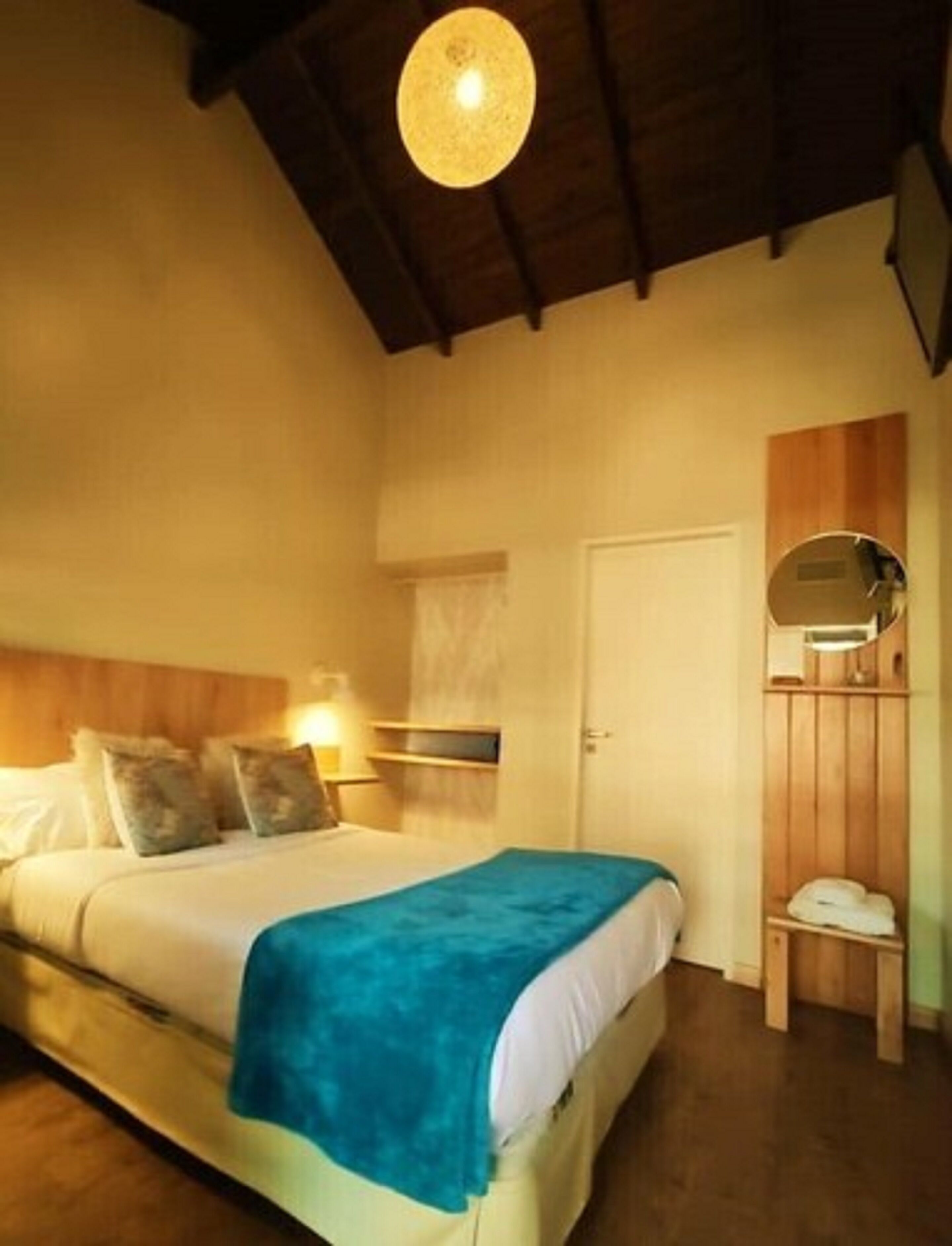 A bedroom with a bed, bedside table, and a mirror.