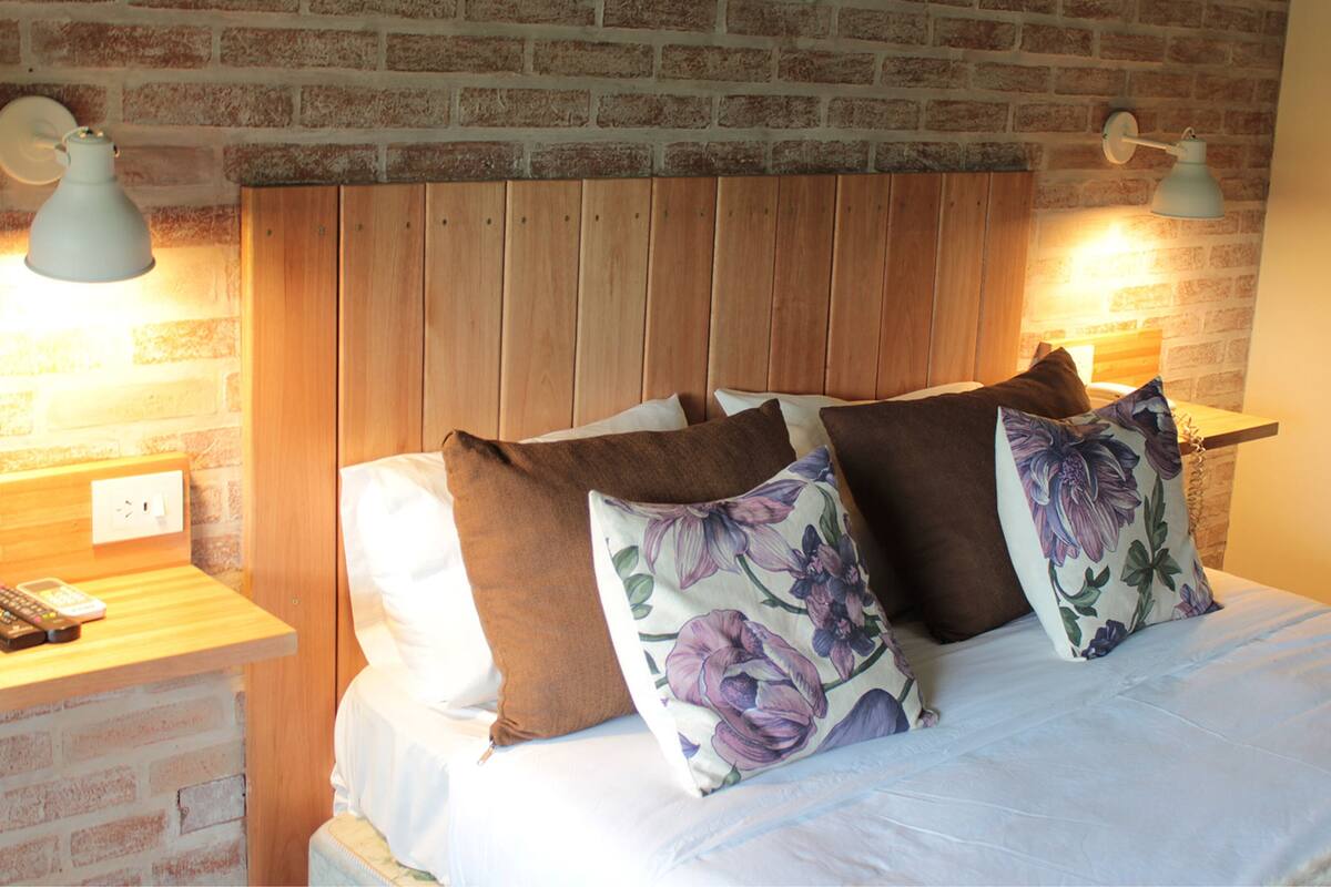 A bed with a wooden headboard, multiple pillows, and bedside lamps.