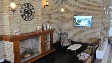 A cozy room with a brick wall, a fireplace, a television, and comfortable seating.