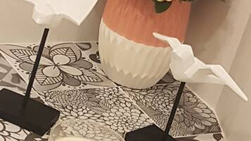 Una mesa con una vela, dos pájaros de papel blanco y un florero con flores.